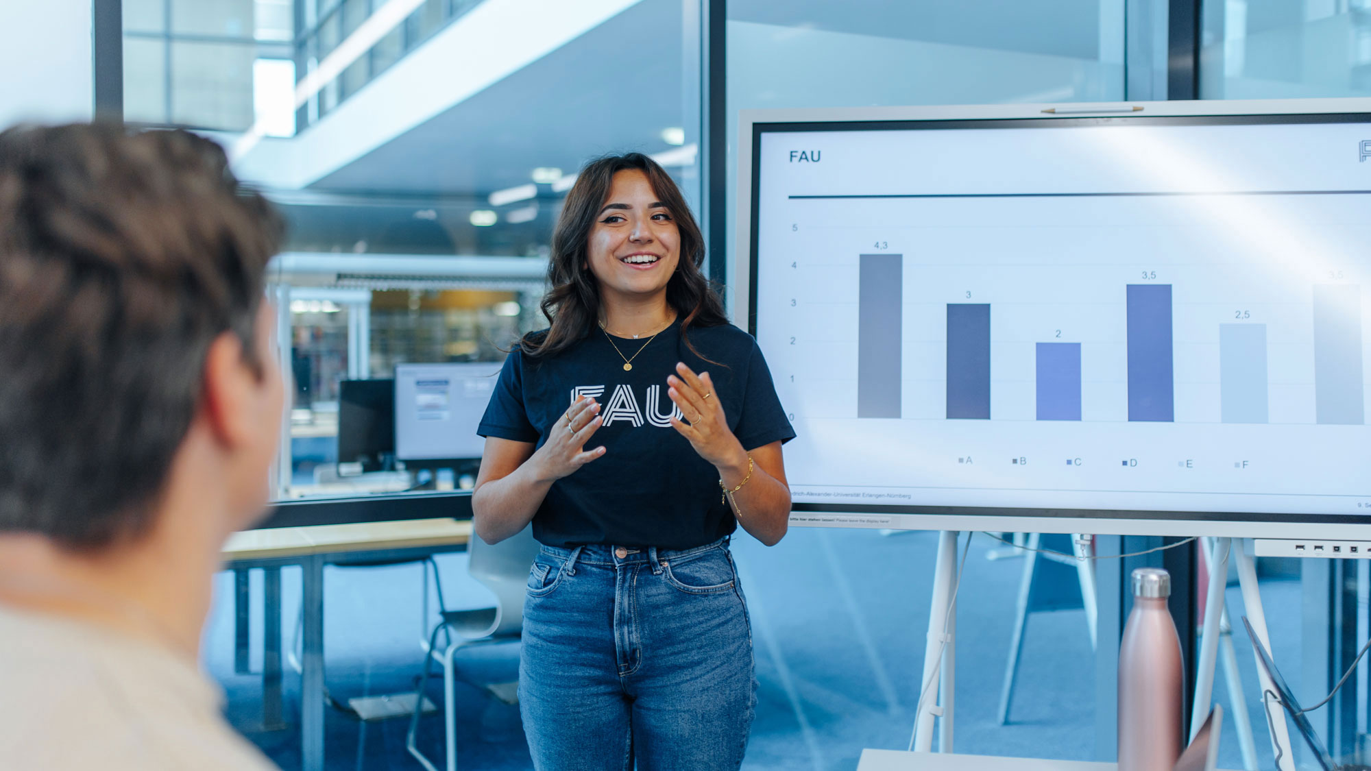 Dozentin steht vor Smartboard und erklärt